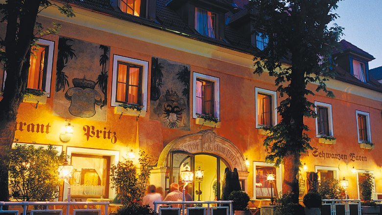 Historic building of the Hotel Zum Schwarzen B&auml;ren at night, illuminated with warm light.