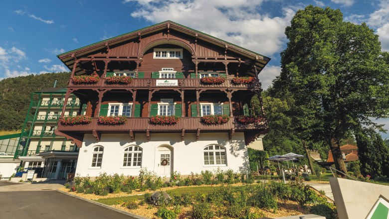 Hotel Schneeberghof with a balcony decorated with flowers and blue sky.