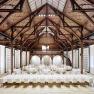 Interior view of a large banqueting hall with wooden beamed ceiling and covered tables.