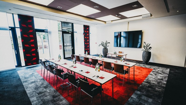 Modern seminar room with tables, chairs and large screen.