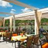 Restaurant terrace with a view of a river and green hills in the background.
