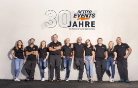 Group of ten people in black clothing in front of a wall with the RETTER EVENTS logo and the text '30 years'.
