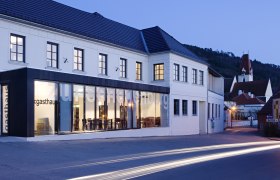 Exterior view of the Gasthof Hotel Zur Schonenburg at dusk with illuminated windows and passing cars.