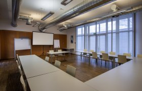 Seminar room with tables, chairs and projection screen.