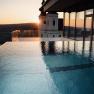 Infinity pool at sunset with a view of a building and the landscape.