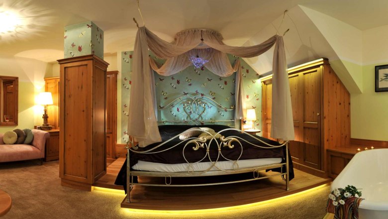 A luxurious bedroom with four-poster bed, wooden furniture and bathtub.