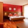 Cozy hotel room with double bed, wooden furniture and red accents.
