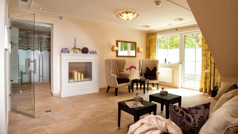 Elegant wellness area with fireplace, armchairs and glass door.