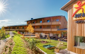 JUFA Hotel Annaberg with playground and sunny sky.
