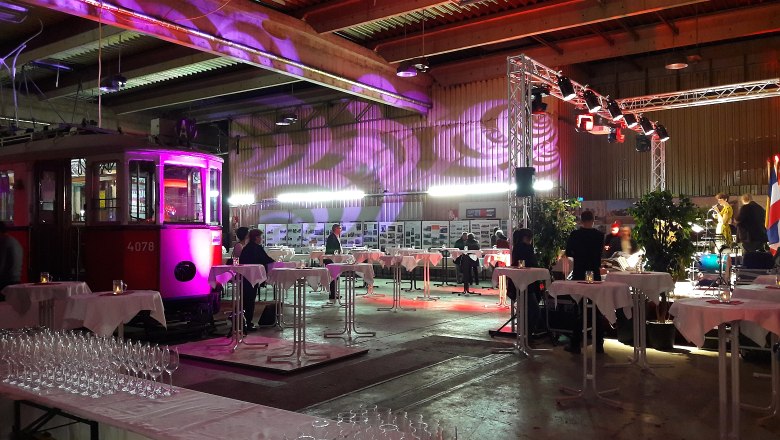 Interior view of an event room with an old streetcar, tables and lighting.