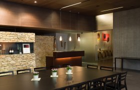 Modern tasting room with wooden table, chairs and stone wall.
