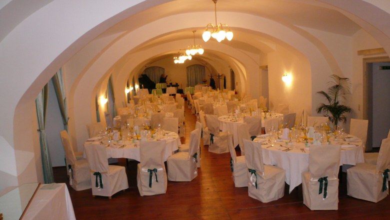 Elegant ballroom with set tables and chairs in Gloggnitz Castle.