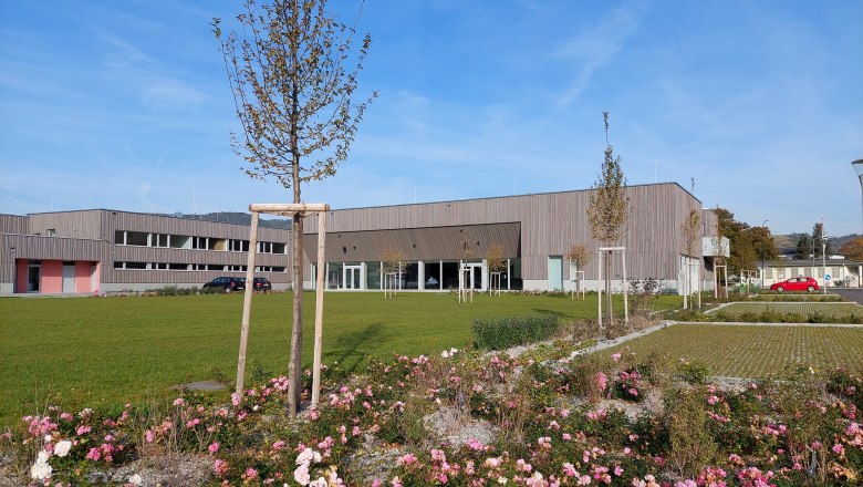 Modern building with wooden façade and well-kept gardens in the foreground.