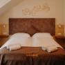 A cozy hotel room with a double bed, featuring light wood paneling and earthy tones.