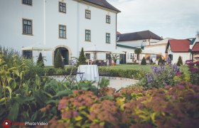 Garden view of Raggendorf Castle with flowers, tables and chairs in the foreground.