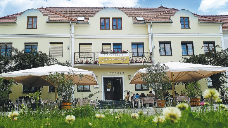 Exterior view of a yellow building with terrace and parasols.