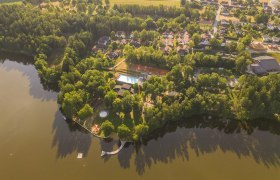 Aerial view of a vacation and theater villa by the lake with trees and buildings.