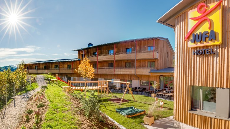 JUFA Hotel Annaberg with playground and sunny sky.