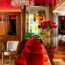 Elegant restaurant with red velvet chairs, chandelier and floral decorations.