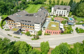 Aerial view of a large hotel complex with several buildings, surrounded by green countryside.