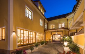 Inner courtyard of the Hotel Zum Schwarzen B&auml;ren with illuminated windows and plants at night.