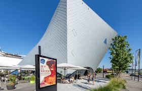 Modern architecture of the Landesgalerie Niederösterreich in Krems with visitors and advertising poster in the foreground.