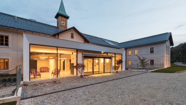 Hochstrass Retreat, © Andreas Buchberger Modern building with glass façade and historic tower in the background.