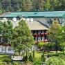 A large hotel building with green roofs and balconies, surrounded by trees and nature.