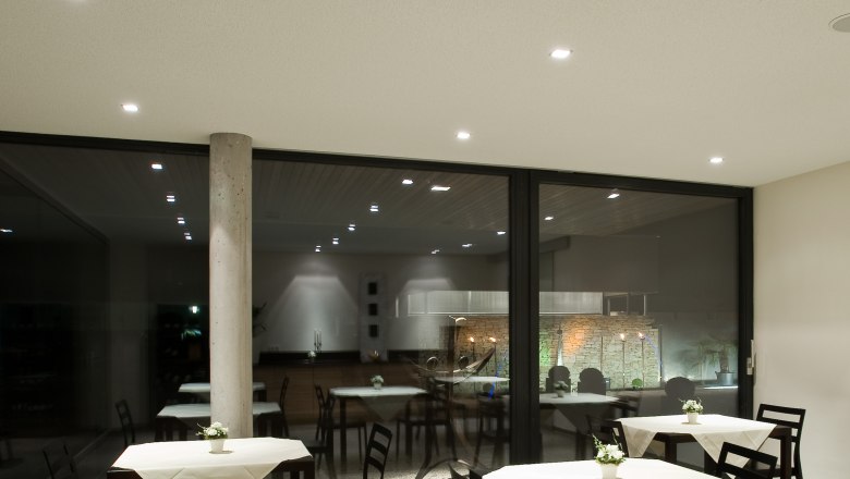 Modern breakfast room with tables and chairs, decorated with white tablecloths and flowers.