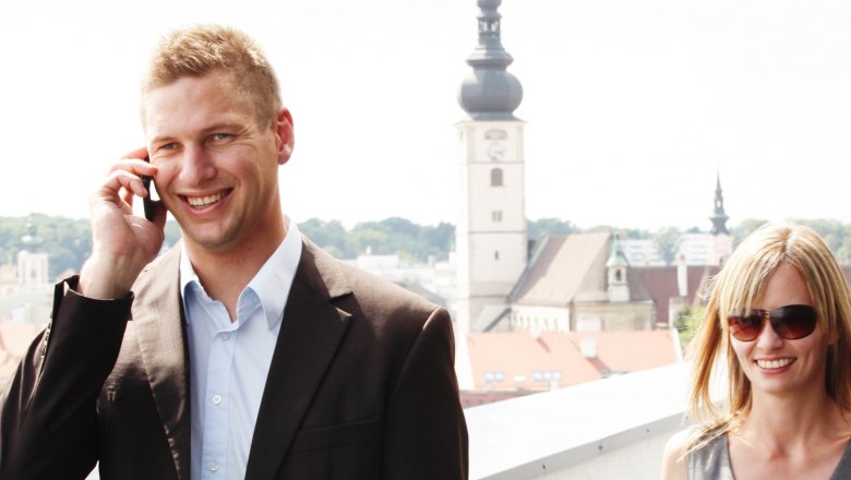 Two people on a terrace with a view of St. Pölten, a church in the background.
