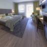 Elegant hotel room with double bed, seating area and large window.