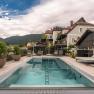 A modern pool on a terrace with a view of the surrounding houses and wooded hills in the background.