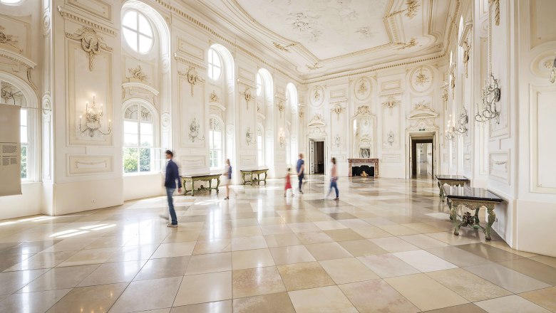 Large, bright ballroom with high windows and ornate walls in the Schloss Hof.