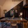 A stylishly furnished room with a table, chairs, a lamp and posters on the wall.