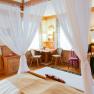 Cozy double room with four-poster bed, wooden furniture and desk.