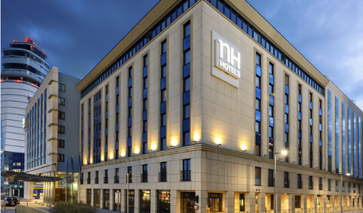 NH Vienna Airport Conference Center at dusk with illuminated building.