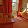 A cozy room with sofa, desk and large window with curtains.
