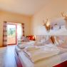 Hotel room with double bed, wooden furniture and balcony with mountain view.