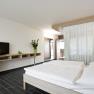 Modern hotel room with double bed, TV and plants.