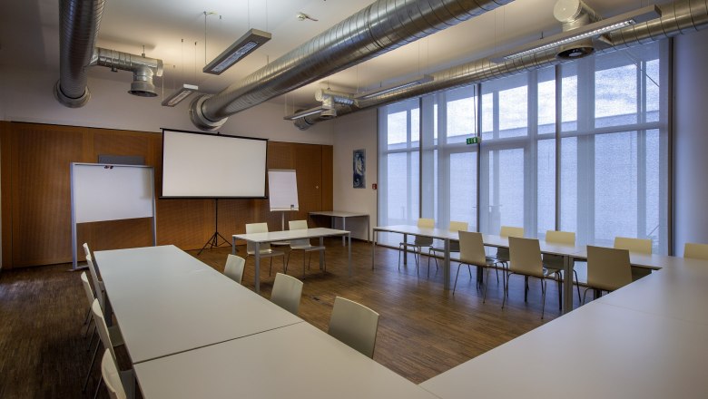 Seminar room with tables, chairs and projection screen.