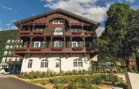 Hotel Schneeberghof with a balcony decorated with flowers and blue sky.