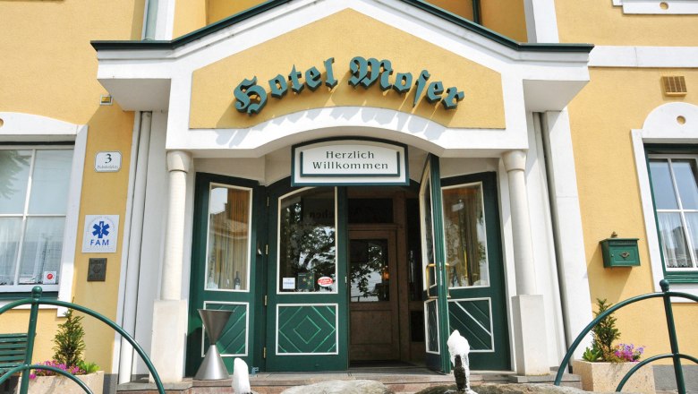 Entrance to Hotel Moser with yellow fa&ccedil;ade and green doors.