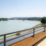 Wooden terrace with a view of a river and green landscape.