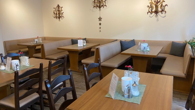 Cozy breakfast area with wooden tables and upholstered benches, decorated with wall ornaments.