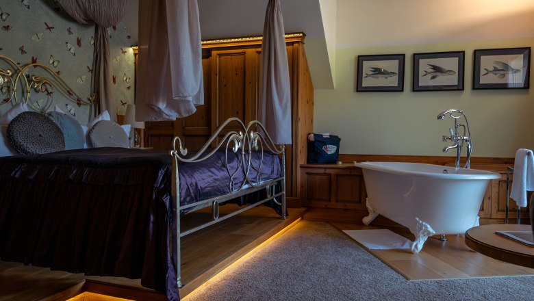 Luxurious hotel room with four-poster bed and free-standing bathtub.