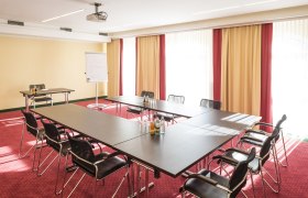 Conference room with U-shaped table, chairs, flipchart and projector.