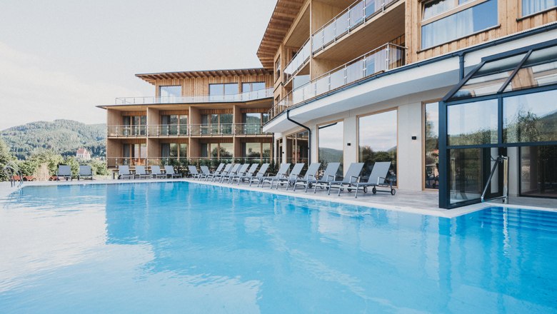 Modern hotel with pool and sun loungers outside.