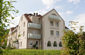 Exterior view of the Hotel Restaurant Donauhof with balconies and garden.
