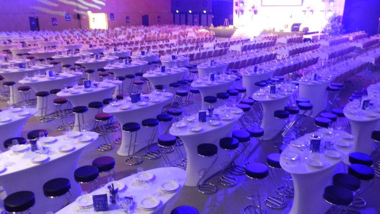 Large hall with covered tables and chairs, illuminated in blue and purple.
