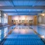 Interior view of an indoor swimming pool with blue water and wall painting.